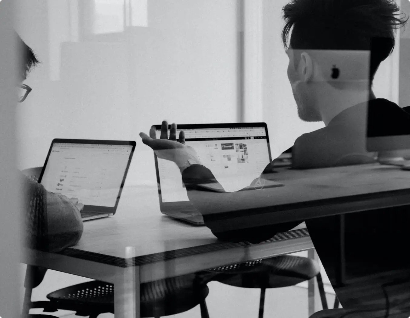 Two people working on laptops at a table, focusing on BigCommerce and SEO.