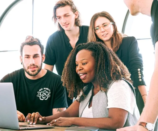 a group of coworkers having a discussion looking at a laptop