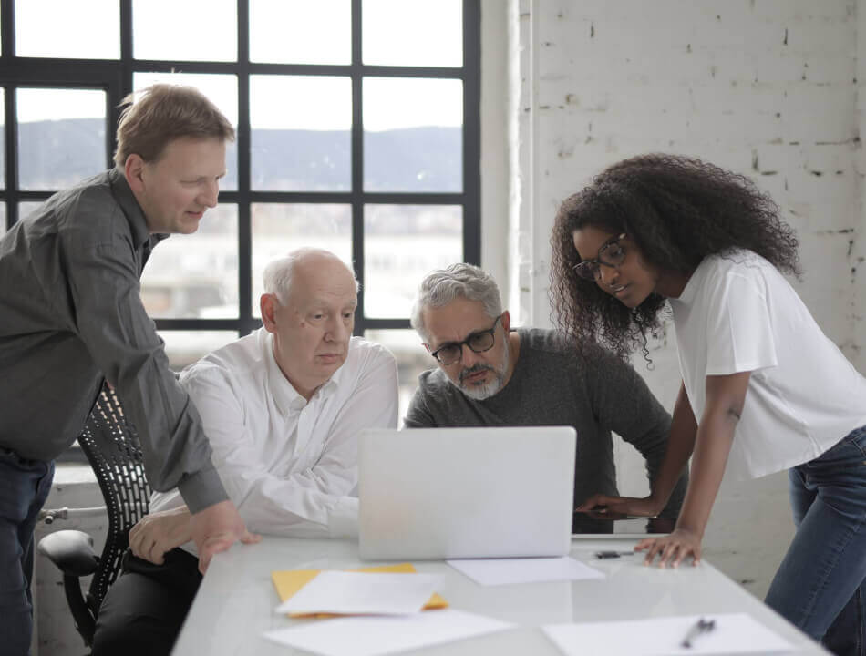 A group four of LinkGraph co-workers looking at a laptop screen.