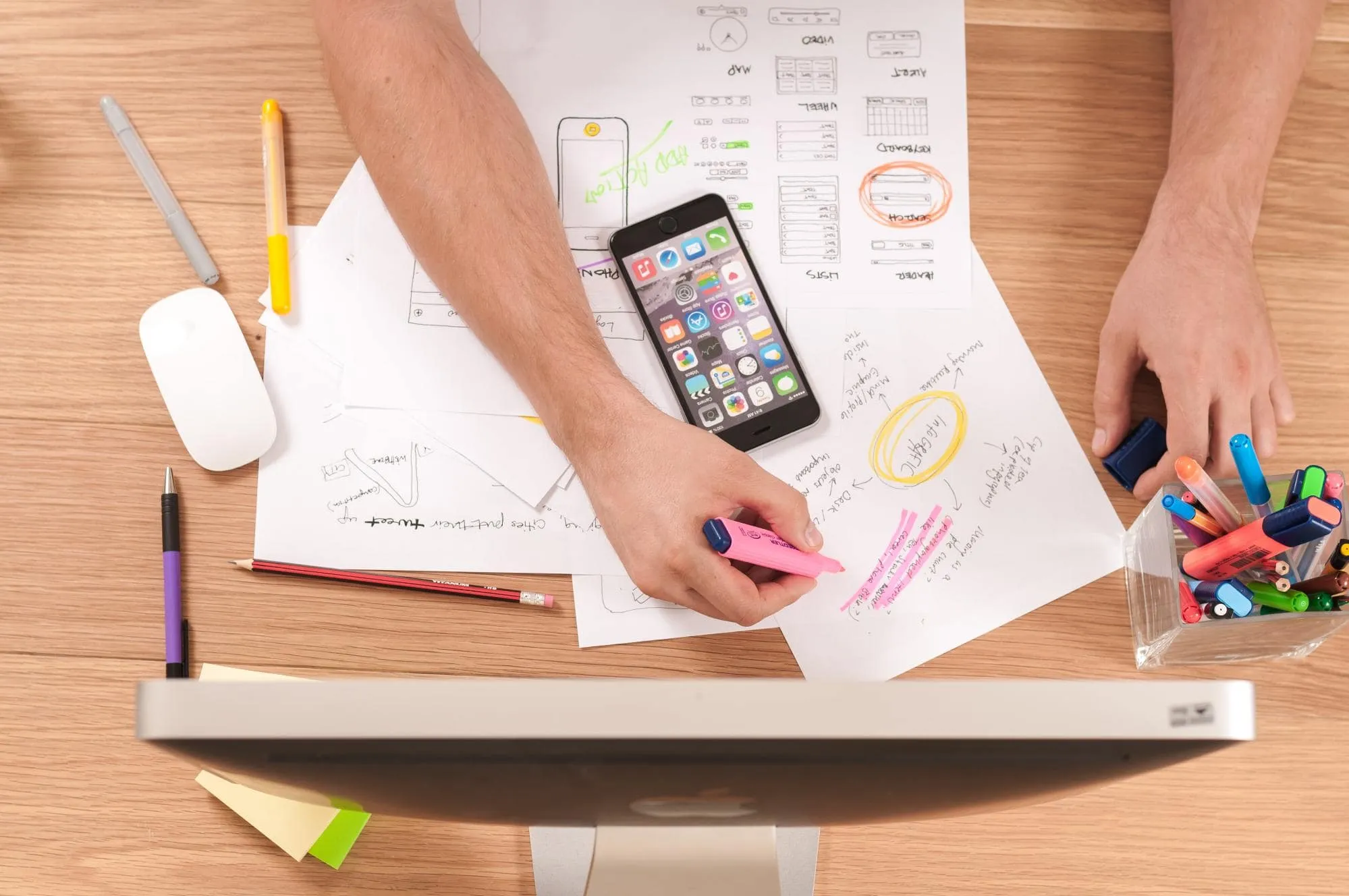 Male arm and hand holding a pink highlighter as he prioritizes an idea on a planning web.