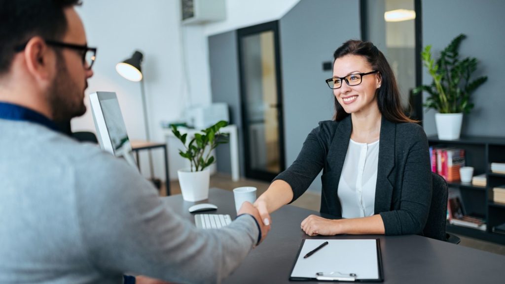 Two professionals shaking hands in an office, symbolizing a partnership built on trust and quality backlink service to enhance SEO rankings.