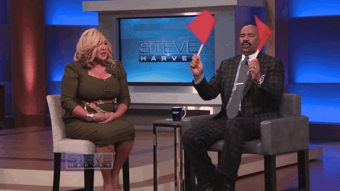Steve Harvey holding up red flags, symbolizing warning signs to watch for when choosing an SEO outsourcing company