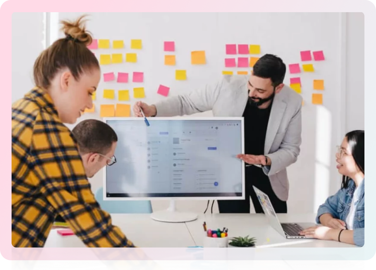 A group of people in a meeting room with sticky notes on the wall, brainstorming ideas.
