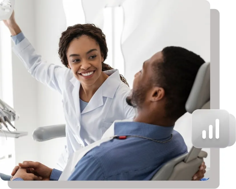 Female dentist smiling and interacting with a male patient seated in a dental chair