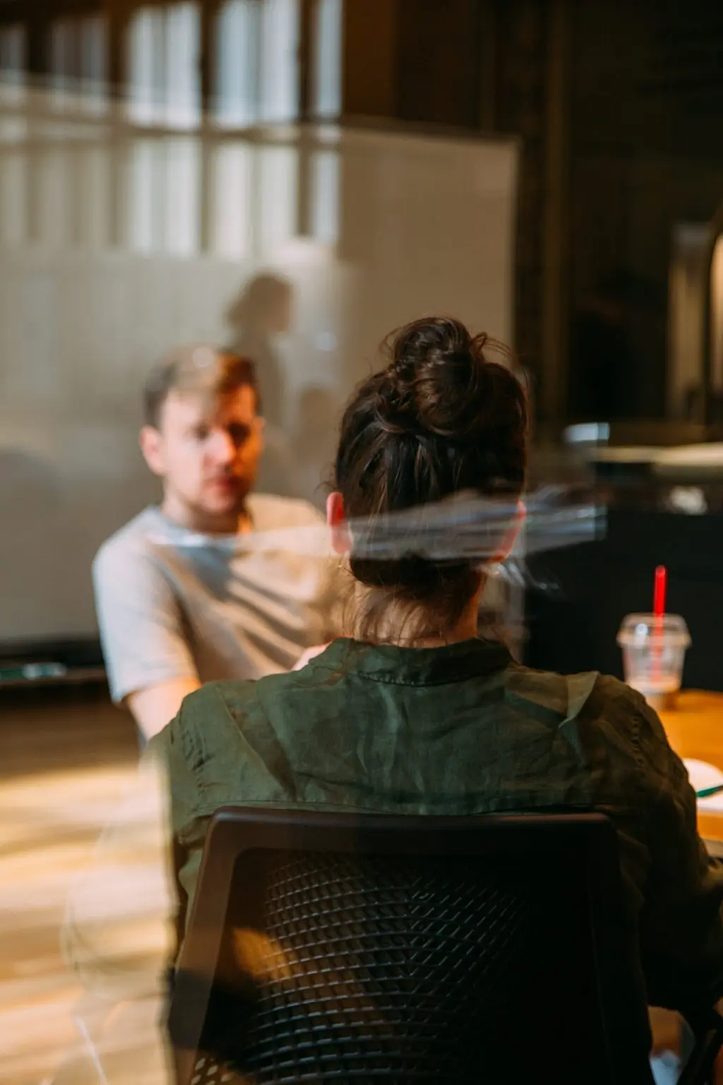 Two colleagues having a focused conversation in a modern office meeting room.