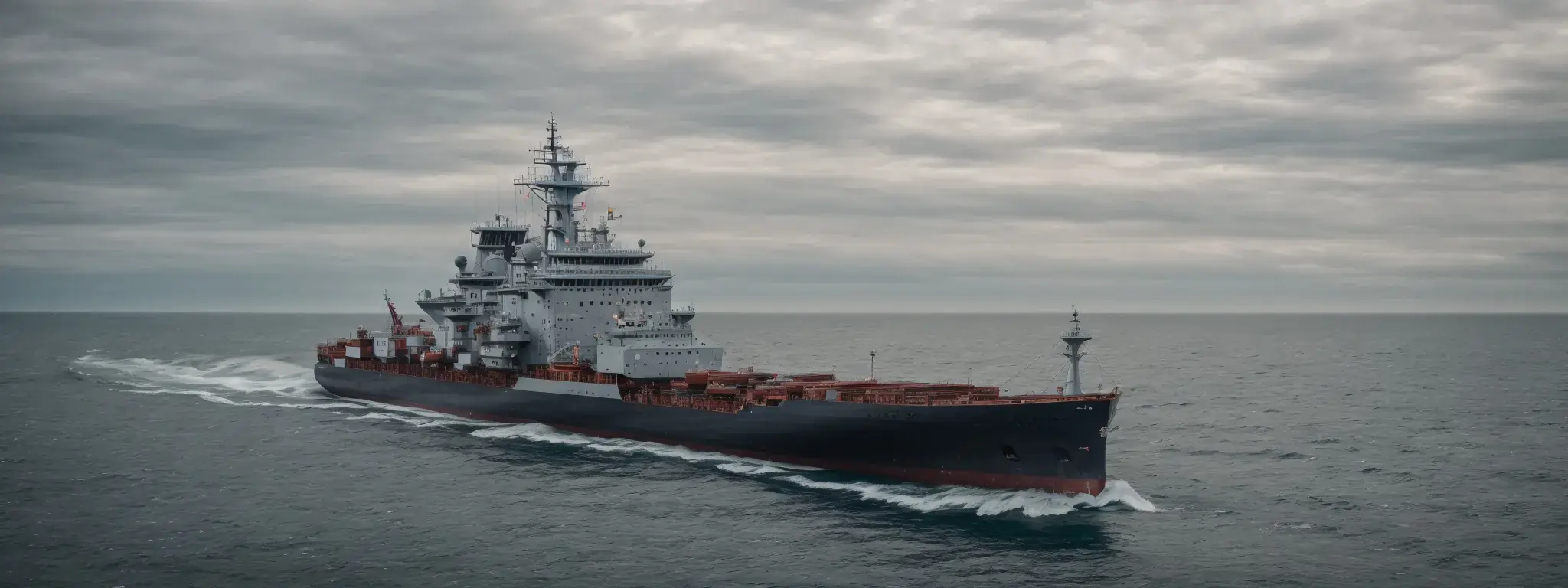 A large modern navy ship sailing through open waters under an overcast sky