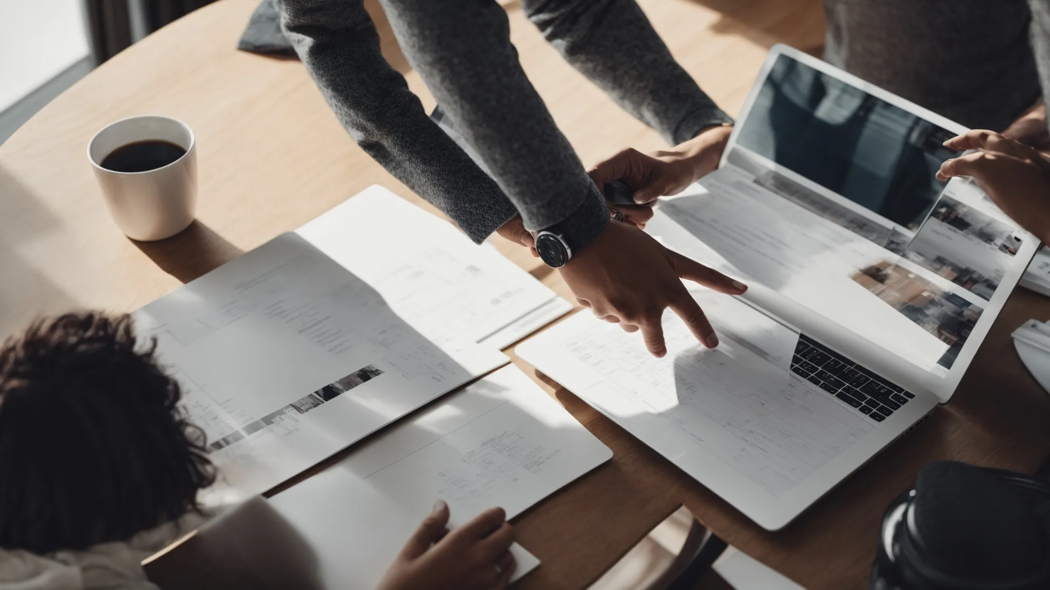 a professional shaking hands across a table during a meeting with digital marketing diagrams visible on a laptop screen.