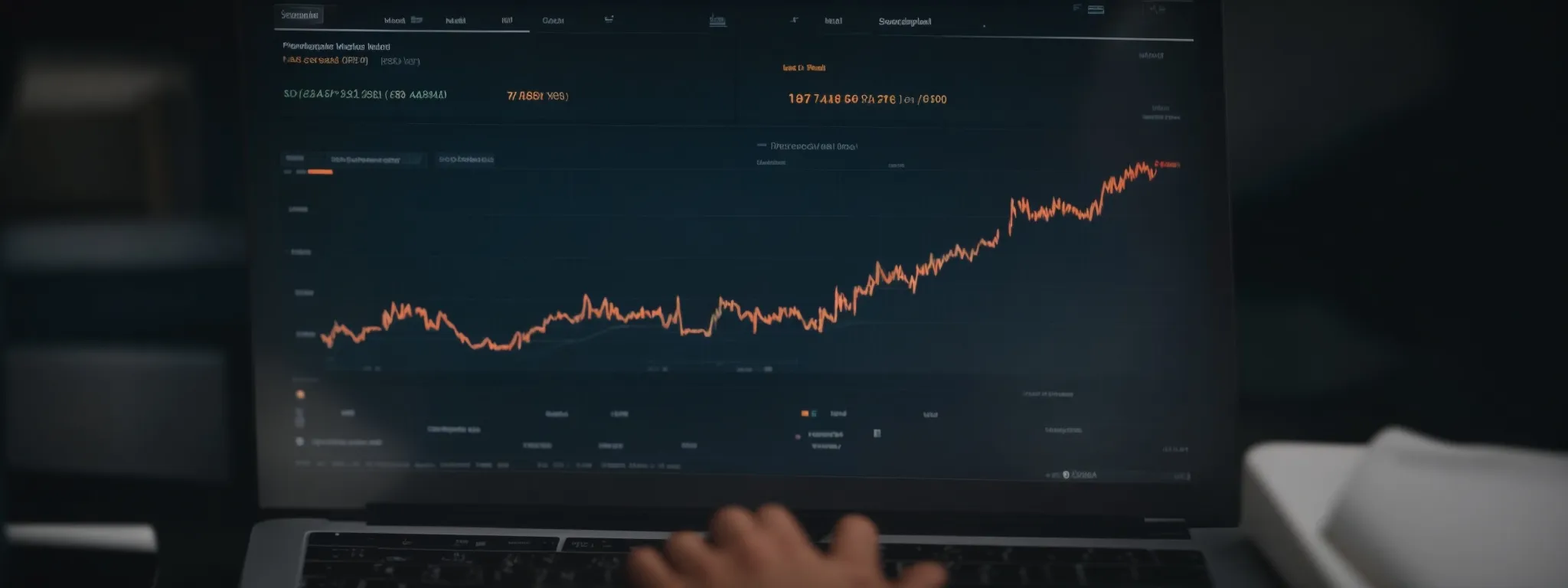 A hand types on a laptop displaying a financial chart with an upward trend and various numerical data on a dark interface.