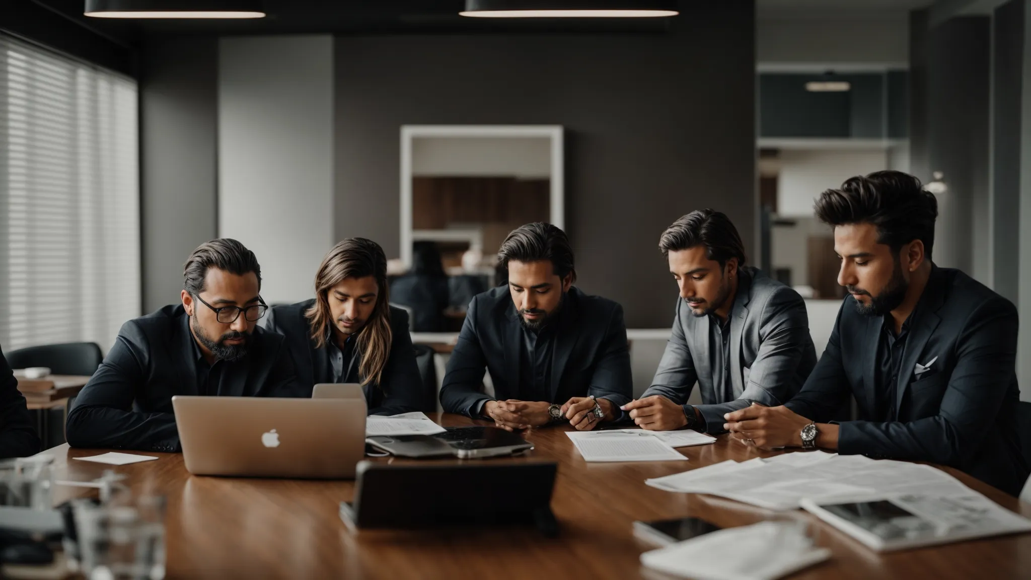 a team of focused professionals gathered around a conference table with a laptop and discussing strategies.