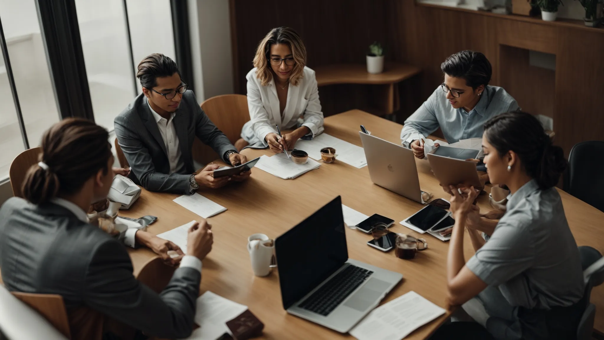 a group of professionals engaged in a lively discussion around a conference table littered with digital devices and seo reports.