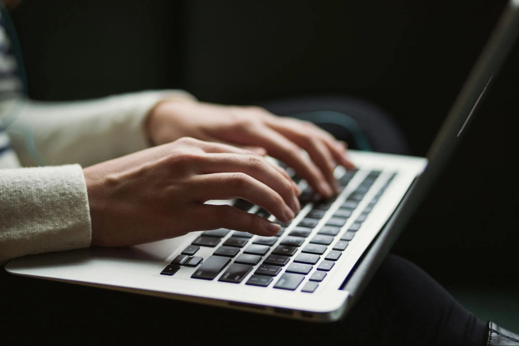 Hands typing on a laptop keyboard, symbolizing content creation, SEO research, and outbound link building for SEO strategy and improving search engine rankings.