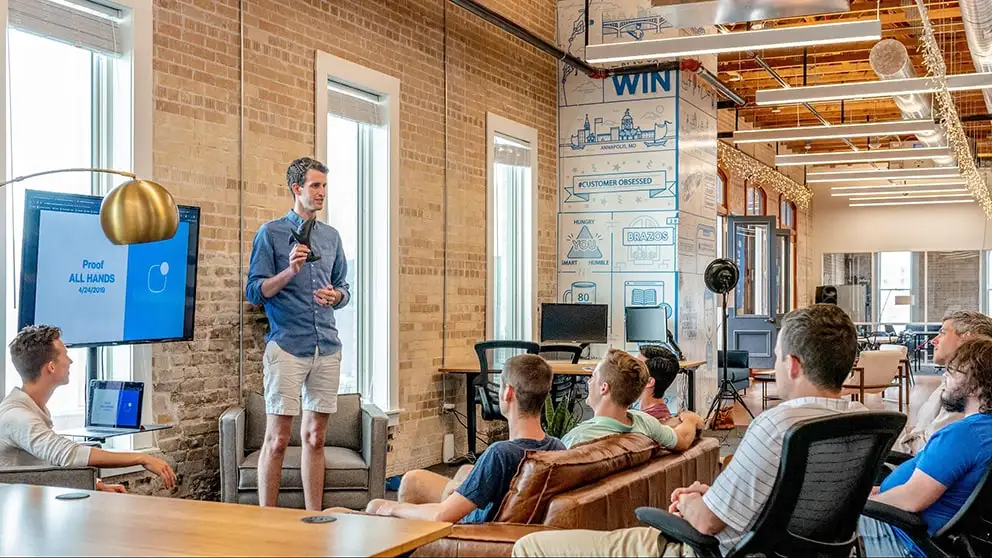 Team attending company presentation during all-hands meeting in modern office